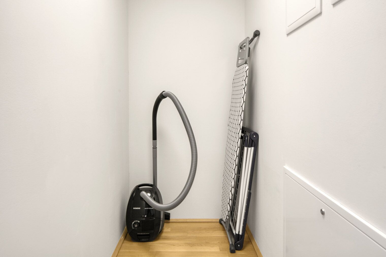 Een hoek van een kamer met een stofzuiger en een radiator.
