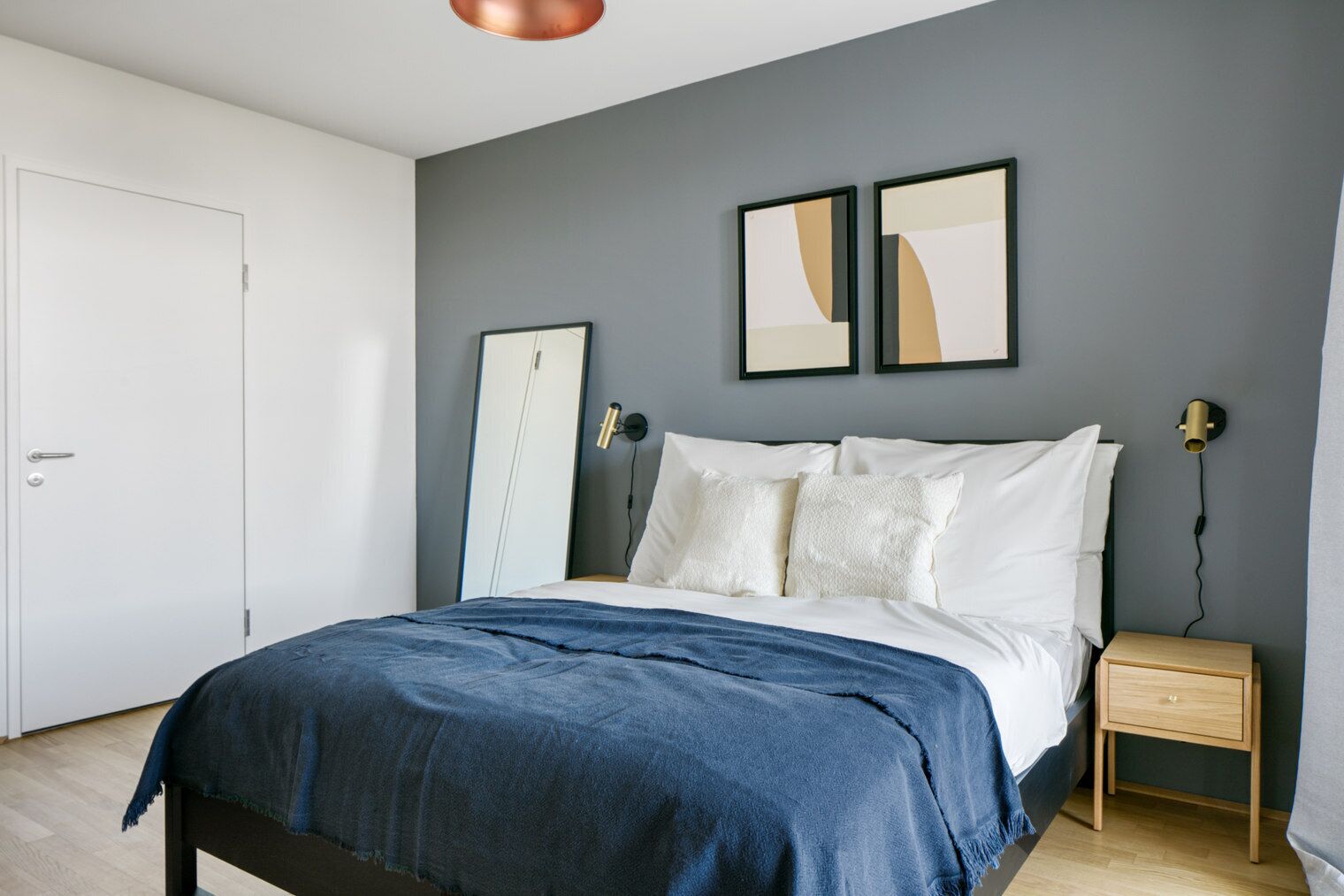 Une chambre à coucher moderne avec un lit, des tables de chevet et des œuvres d’art accrochées au mur.
