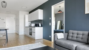 A modern living room with a grey sofa, a black coffee table, and a white rug.