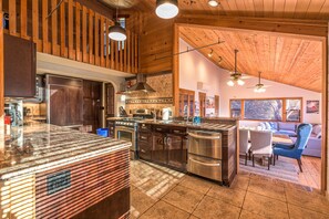 A spacious kitchen with wooden accents, a dining area with a sofa and chairs, and a large window providing natural light.