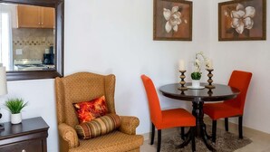 A dining area with a round table, two orange chairs, a brown armchair, and a small side table with a plant. - 
5 min drive to Junkanoo Beach, Arawak Cay, Ardastra Garden & Zoo & Attractions (Nassau)