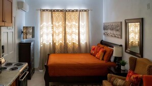 A compact bedroom with a bed, a chair, a nightstand, a lamp, and a painting on the wall. - 
5 min drive to Junkanoo Beach, Arawak Cay, Ardastra Garden & Zoo & Attractions (Nassau)