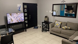 Un salon avec un téléviseur, un canapé, une table basse et une porte.