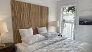 Un dormitorio con una cama grande, dos lámparas de noche, un cabecero de madera y una ventana con vistas a zonas verdes.