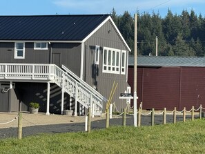 A two-story building with a porch and a staircase leading to the entrance.
