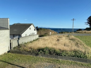 A coastal house with a grassy yard and a view of the ocean.