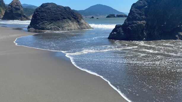 Una playa con rocas grandes y cielo despejado.