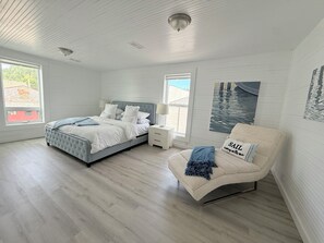 A bedroom with a bed, a nightstand, a chair, and a window.