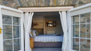 A bedroom with a bed, a dresser, and a radiator. - Magical 3-Bed Stone Built Cottage - Sleeps 6 (Down)