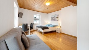 Une chambre avec un plafond en bois, un lit, un bureau, une chaise et un canapé.