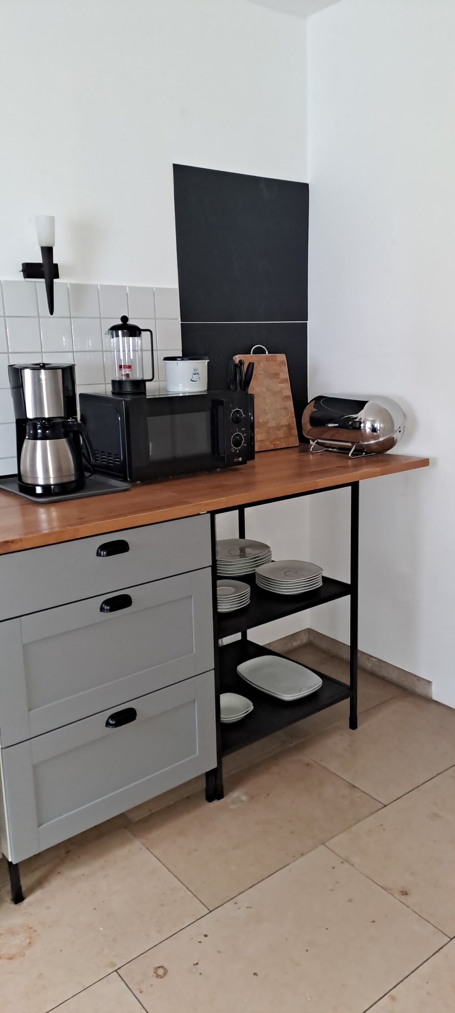 A kitchen with a coffee maker, microwave, and storage shelves.