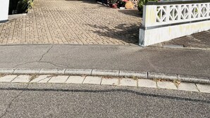 Une maison à deux étages avec un garage, une façade en briques et un toit recouvert de tuiles.