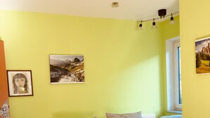 Un salon moderne avec un canapé blanc, une table basse en verre et un mur jaune vif.