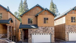 A log cabin with a stone foundation, a garage, and a covered entryway.