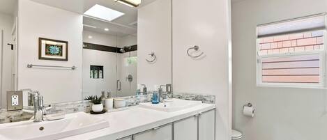 Un baño moderno con dos lavamanos, un espejo grande y un inodoro.