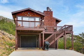 Une cabane à deux étages avec un balcon, un escalier et un garage.