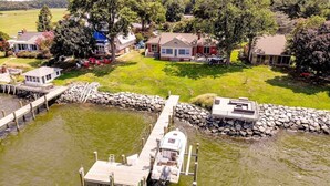 A lakeside property with a dock, a small boat, and several houses with outdoor seating areas.