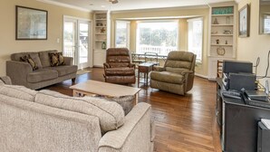 A spacious living room with a sofa, two recliners, a coffee table, and a TV stand.