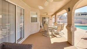 A covered patio area with a dining table and chairs, a ceiling fan, and a view of a swimming pool. - Lake Havasu Home - 2 Mi from Main Launch Ramp! (Lake Havasu City)