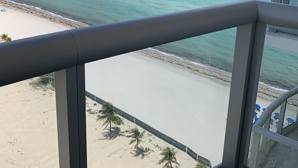 Un balcon avec vue sur une plage et l’océan.