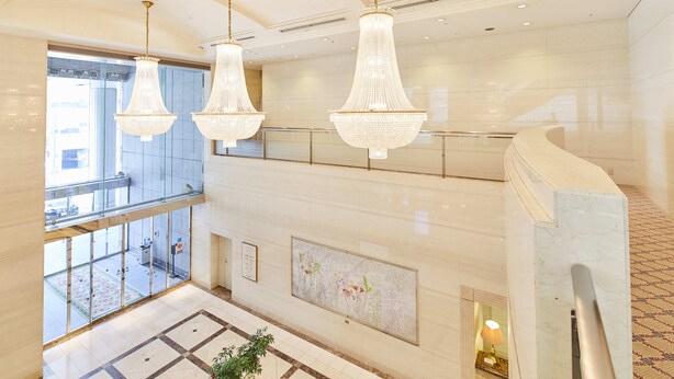 A spacious lobby with a high ceiling, large chandeliers, a glass railing, and a tiled floor. - Hotel Le Port Kojimachi (Tokyo)