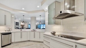 A modern kitchen with white cabinetry, a stainless steel dishwasher, and a central island with a sink.