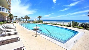 A swimming pool with lounge chairs and a view of the ocean.