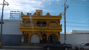 A yellow building with a distinctive architectural style, featuring arched windows and a central entrance. - Hotel Kiko (Mazatlán)