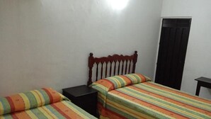 A room with two beds, each with a striped bedspread, a wooden headboard, and a black nightstand. - Hotel Kiko (Mazatlán)