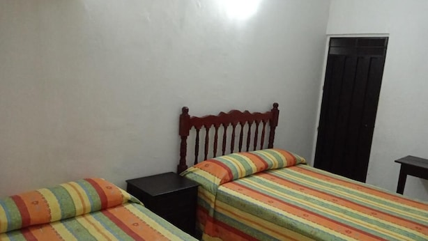A room with two beds, each with a striped bedspread, a wooden headboard, and a black nightstand. - Hotel Kiko (Mazatlán)
