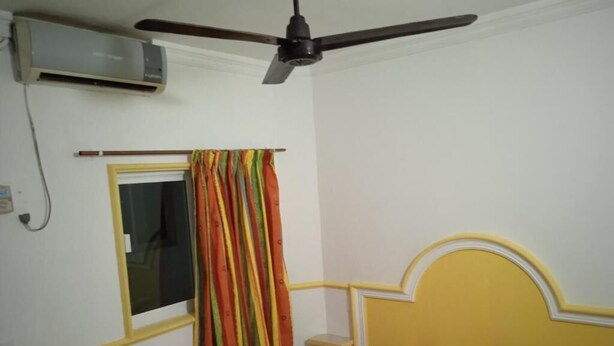 A bedroom with a bed, a window with curtains, a ceiling fan, and an air conditioning unit. - Hotel Kiko (Mazatlán)