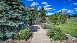 A pathway leading through a garden with a wooden pergola, surrounded by various shrubs and trees. - Stunning Views, Foosball, Outdoor Fireplace, 30 Min to Wolf Creek Ski Resort! (Pagosa Springs)