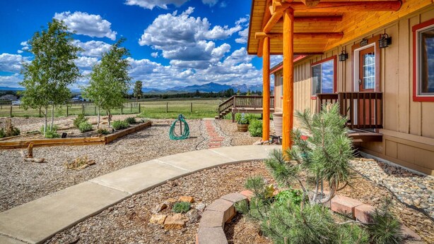 A wooden building with a covered porch, a gravel pathway, and a view of mountains in the background. - Stunning Views, Foosball, Outdoor Fireplace, 30 Min to Wolf Creek Ski Resort! (Pagosa Springs)