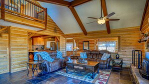 A spacious log cabin interior with a high ceiling, a dining area, a living room with leather sofas, and a fireplace. - Stunning Views, Foosball, Outdoor Fireplace, 30 Min to Wolf Creek Ski Resort! (Pagosa Springs)