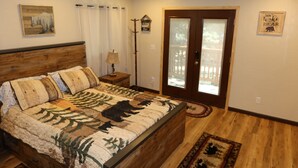 Une chambre avec un lit en bois, un ventilateur de plafond, une porte avec des panneaux de verre et une décoration murale sur le thème des ours.