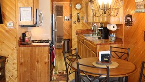 L’intérieur d’un chalet en bois comprend une cuisine, un coin repas et une cheminée.