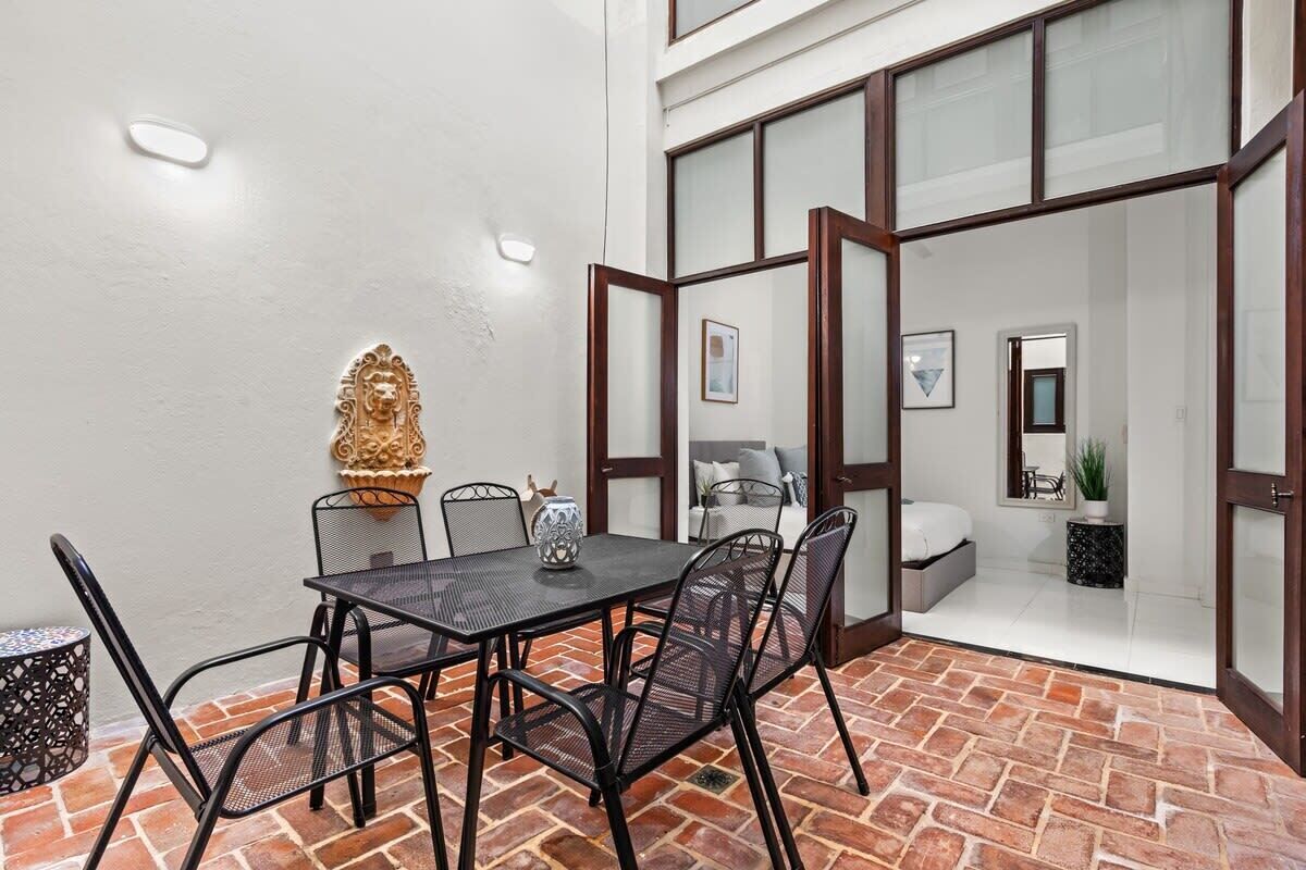 Un coin repas avec un sol en briques, une table entourée de chaises et un vase décoratif.