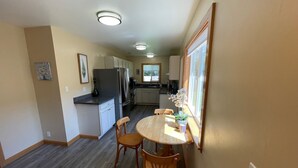 Una cocina compacta con comedor, sillas de madera, una mesa redonda y un refrigerador.