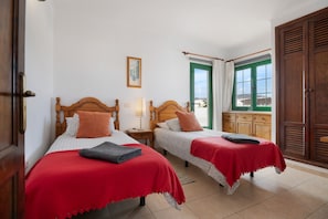 Una camera d'albergo con due letti, un armadio in legno, una finestra con tende e vista sull'esterno.