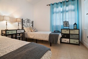 Une chambre avec deux lits, une table de chevet avec des lampes, une commode avec des tiroirs et une fenêtre avec des rideaux.