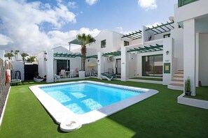 A modern hotel with a swimming pool, outdoor seating, and a covered patio area. - "Apt 2 Las Palmeras III Lanzarote" with Sea and Mountain Views, Shared Pool, Private Terrace & Wi-Fi (Puerto del Carmen)