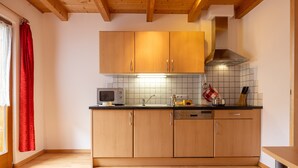 Una cocina con armarios de madera, microondas, pileta y estufa.