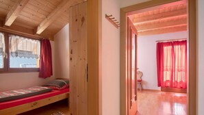 Una habitación de madera con una cama, una mesita y una silla.