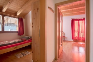 A wooden room with a bed, a small table, and a chair.