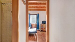 A narrow hallway leading to a bedroom with a bed, a television, and a shelf with items. - Holiday Apartment "Talblick Hinterproslhof" with Mountain View, Balcony & Wi-Fi (Sarentino)