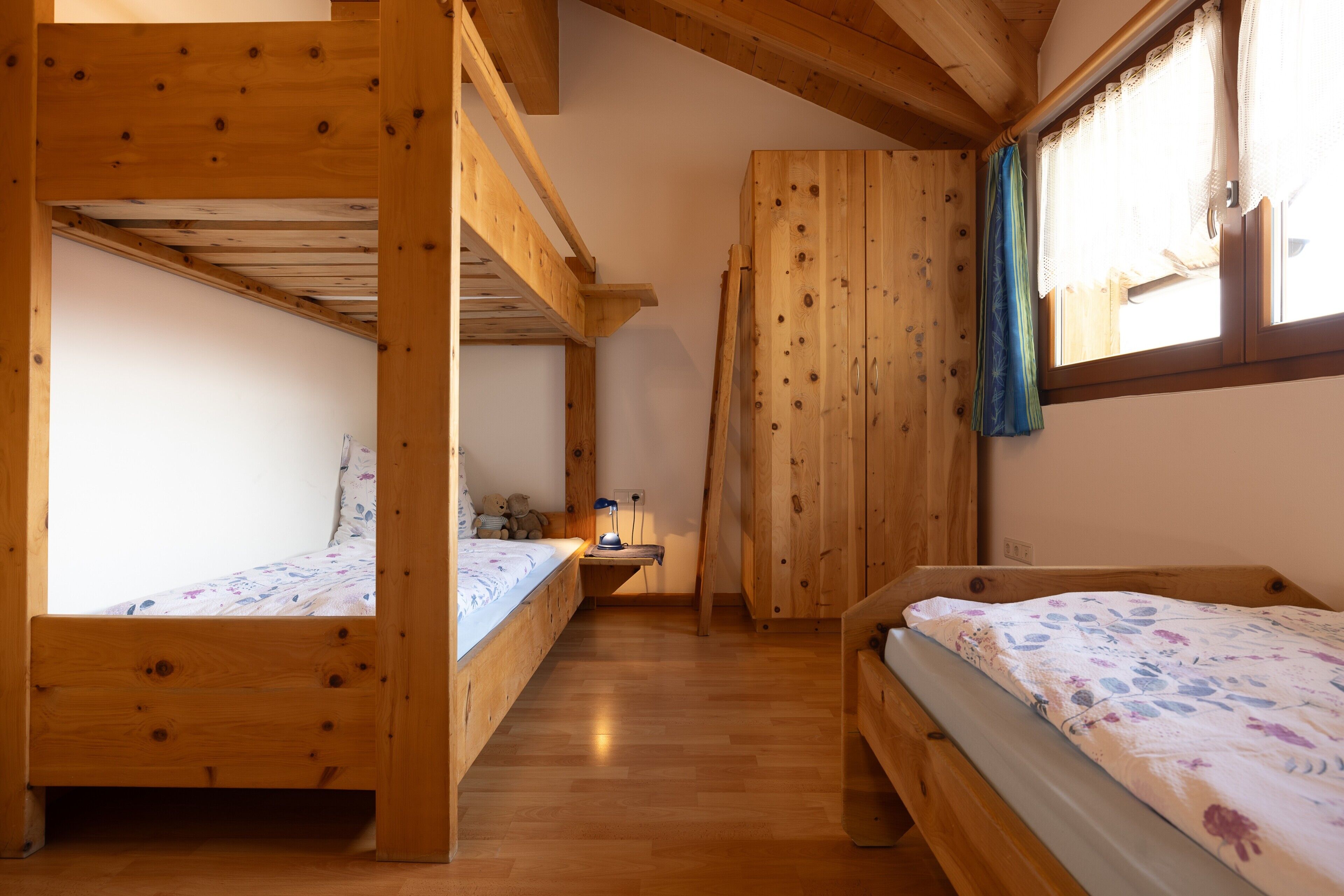 Una stanza in legno con letti a castello, una scrivania e una finestra con tende.