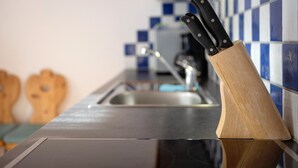 A kitchen counter with a knife block, a sink, and blue and white checkered backsplash. - Holiday Apartment "Talblick Hinterproslhof" with Mountain View, Balcony & Wi-Fi (Sarentino)