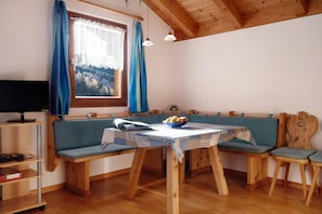 Una mesa de comedor de madera con mantel azul, bancos de madera y una ventana con cortinas.