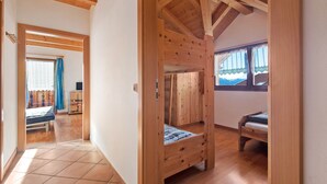 A wooden interior with a bed, a desk, and a window with curtains. - Holiday Apartment "Talblick Hinterproslhof" with Mountain View, Balcony & Wi-Fi (Sarentino)
