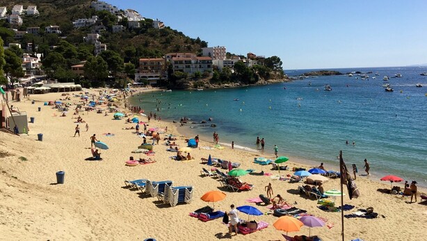 Una playa con tumbonas, sombrillas y gente.